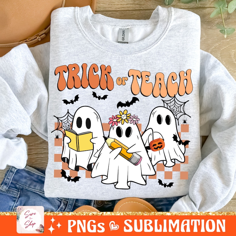 May include: A grey sweatshirt with the text "Trick or Teach" in a retro font. Three cartoon ghosts are depicted, one holding a book, one holding a pencil, and one holding a pumpkin.
