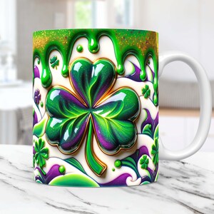 May include: White ceramic mug with a green shamrock design. The shamrock is dripping with green glitter and has a gold outline. The background is white with purple and green swirls.