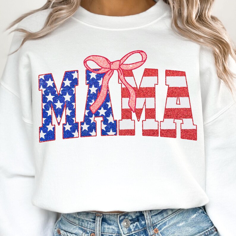May include: White sweatshirt with a red, white, and blue "MAMA" graphic with a pink bow on top. The letters are in a glittery font.