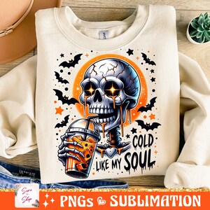 May include: A white sweatshirt with a graphic of a skeleton drinking a cold beverage. The skeleton has glowing eyes and is dripping with a golden liquid. The text on the sweatshirt reads "Cold Like My Soul".