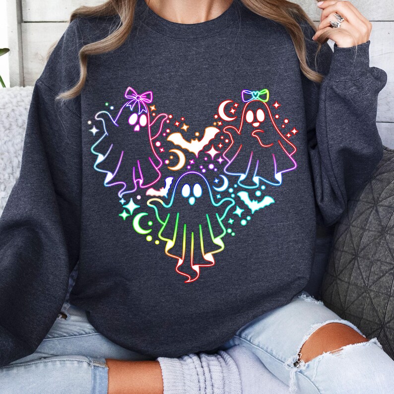 May include: A dark gray sweatshirt with a rainbow-colored design of three ghosts with bows and bats. The ghosts are arranged in a heart shape.