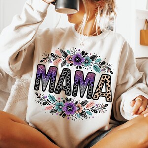 May include: White sweatshirt featuring a floral design and the word "MAMA" in black with a leopard print and glitter accents.