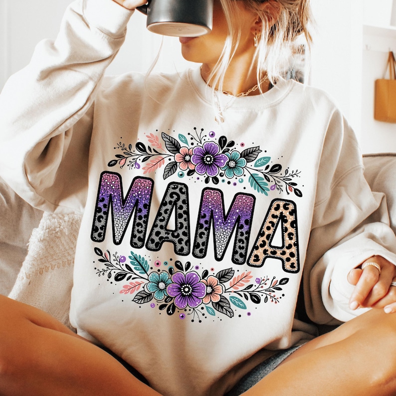 May include: White sweatshirt featuring a floral design and the word "MAMA" in black with a leopard print and glitter accents.