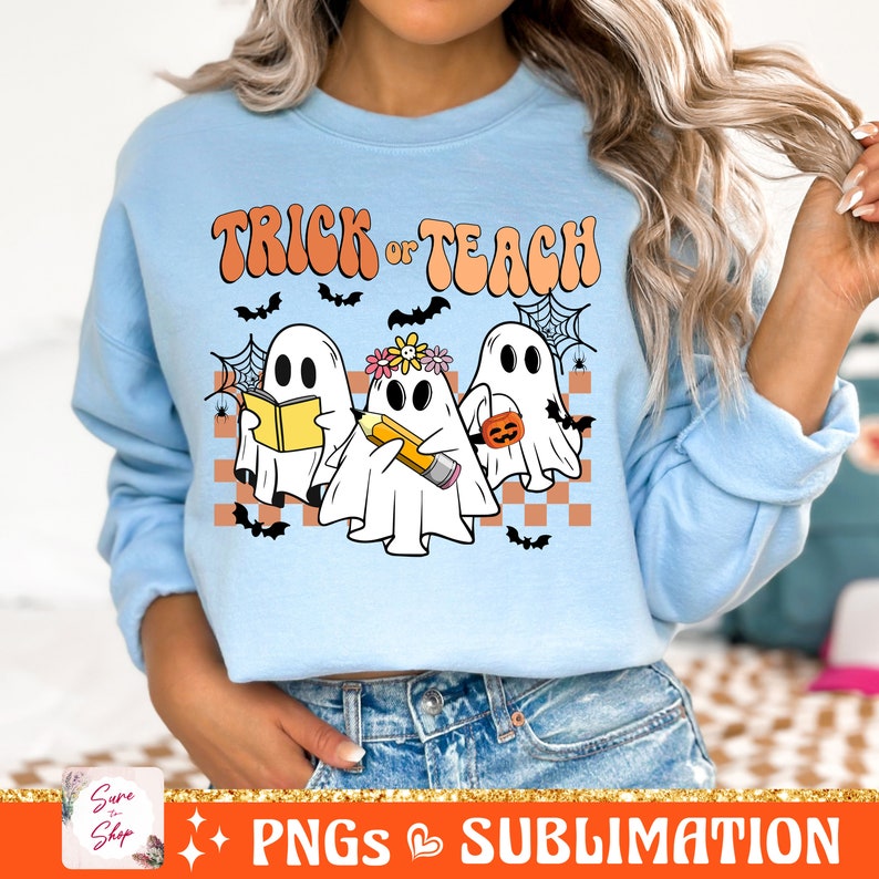 May include: A light blue sweatshirt featuring a design of three ghosts. The ghosts are holding a book, a pencil, and a pumpkin. The text "Trick or Teach" is above the ghosts.