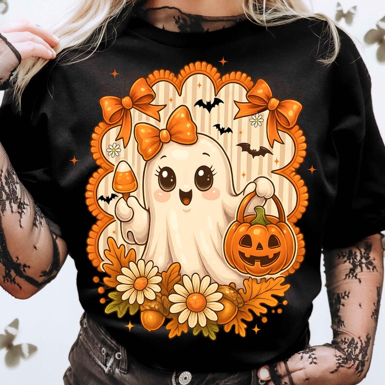 Pode incluir: Camiseta preta com um fantasma de desenho animado segurando doces e uma lanterna de ab&oacute;bora. O design inclui la&ccedil;os laranja, morcegos, flores e folhas de outono, dentro de uma borda ondulada.