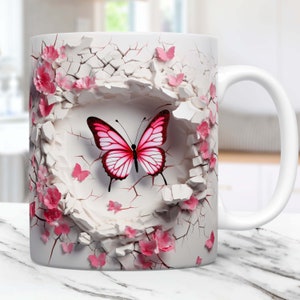 May include: White ceramic mug featuring a pink butterfly design. The butterfly is surrounded by pink flowers against a cracked white background.