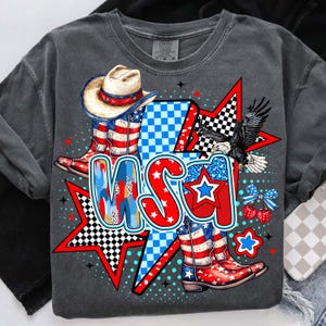May include: A gray t-shirt with a graphic design featuring a cowboy hat, boots, stars, and the word "USA" in red, white, and blue.