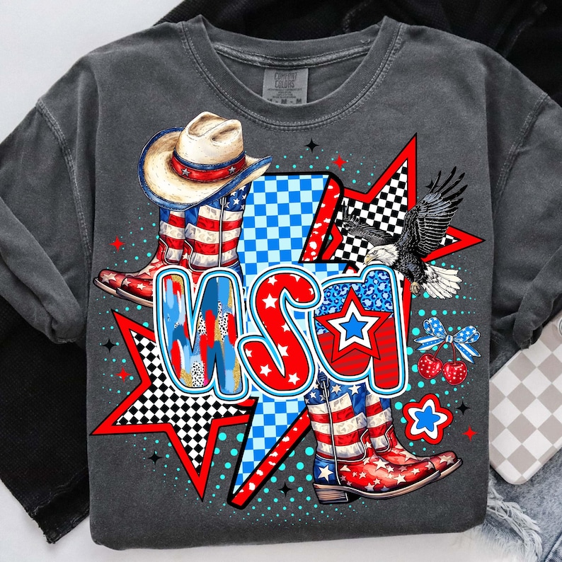 May include: A gray t-shirt with a graphic design featuring a cowboy hat, boots, stars, and the word "USA" in red, white, and blue.