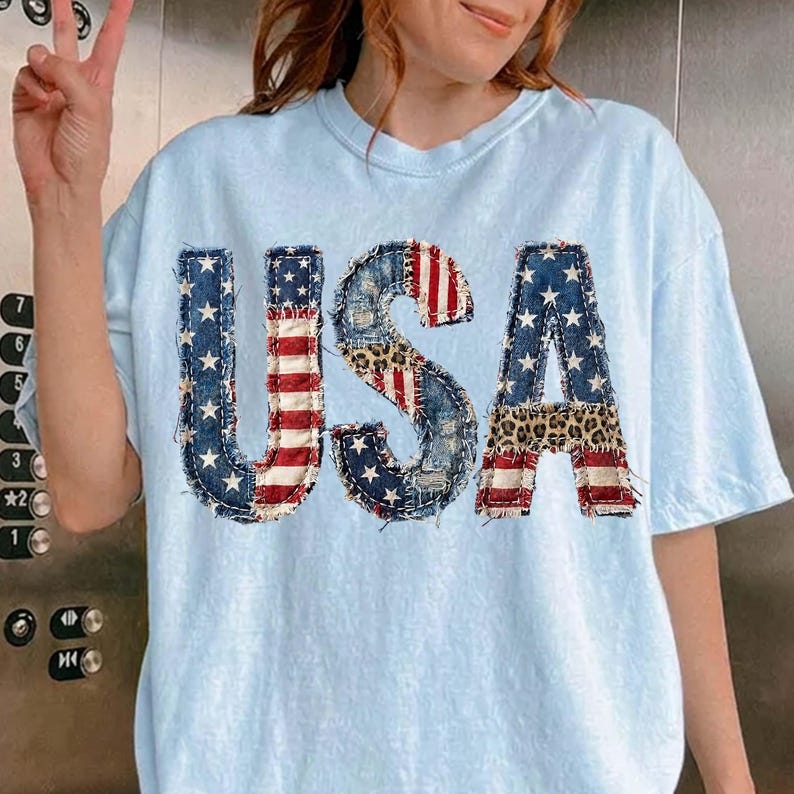 Pu&ograve; includere: T-shirt azzurra con la scritta "USA" in un design patchwork. Le lettere presentano denim, stampa leopardata e la bandiera americana. La maglietta ha maniche corte e girocollo.