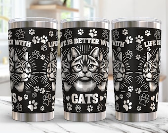 Puede incluir: Un vaso de acero inoxidable con fondo negro y huellas de patas blancas. El vaso tiene el texto "Life is better with cats" impreso en él. El vaso está rodeado por un borde blanco.