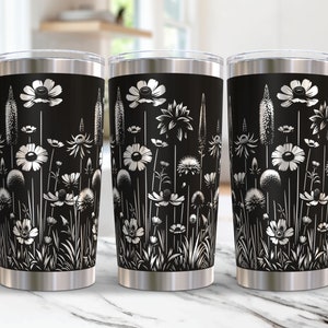 May include: Three stainless steel tumblers with a black background and a white floral design. The tumblers are all the same size and shape.
