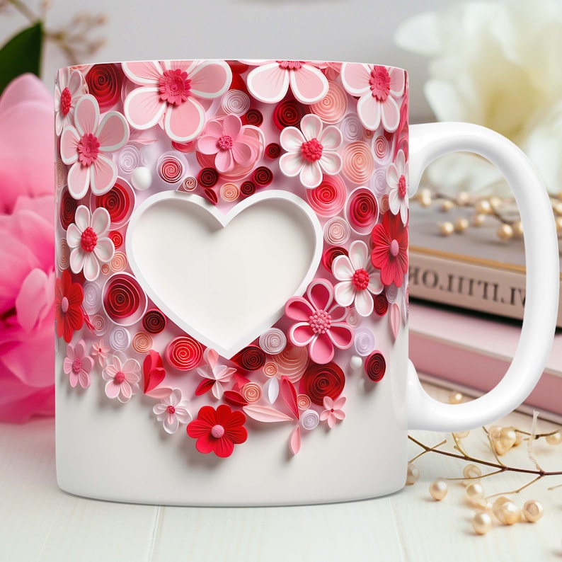 May include: White ceramic mug decorated with a heart-shaped cutout and a floral design. The flowers are in shades of pink and red, with a 3D effect. The mug has a white handle and is set against a soft background.