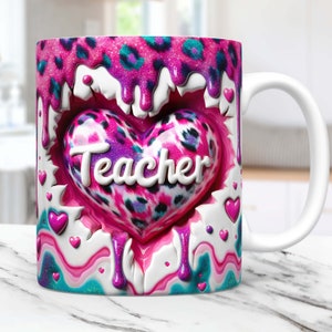 May include: White ceramic mug with a pink, blue, and teal design. The design features a heart with a leopard print and the word "Teacher" inside. The heart is surrounded by pink and blue dripping paint.