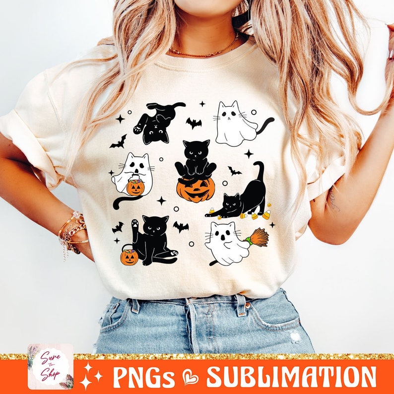 以下が含まれることがあります： ハロウィン用のコスチュームを着た猫の白黒のデザインが施された白いTシャツ。猫は、幽霊、魔女、カボチャなど、さまざまなコスチュームを着ています。デザインはシャツに複数回繰り返されています。