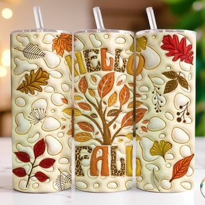 May include: Three stainless steel tumblers with a white background and fall-themed designs. The tumblers feature a leopard print design with the words "Hello Fall" on the middle tumbler. The tumblers have a white background with brown, orange, and red leaves and other fall-themed designs.