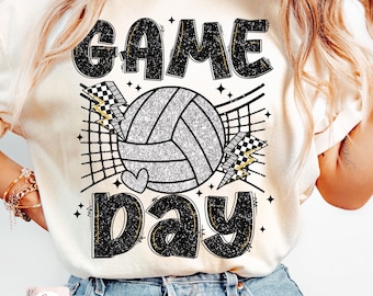 May include: A white t-shirt with a black and silver glitter design that says "GAME DAY" with a volleyball and a net.