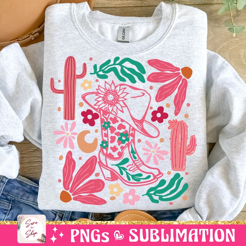 May include: A light gray sweatshirt featuring a colorful graphic design. The design includes a cowboy boot, hat, cacti, flowers, and leaves in shades of pink, green, and orange. The text "PNGs Sublimation" is at the bottom.