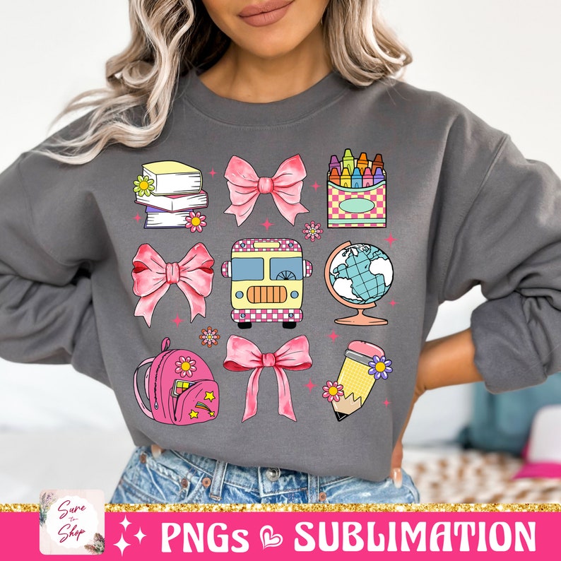 May include: A gray sweatshirt with a colorful design featuring a school bus, books, a globe, a pencil, a backpack, crayons, and bows. The design is perfect for back to school season.