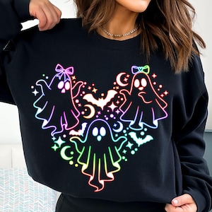 May include: Black sweatshirt with a rainbow-colored design of three ghosts with bows on their heads. The ghosts are arranged in a heart shape with stars and bats around them.