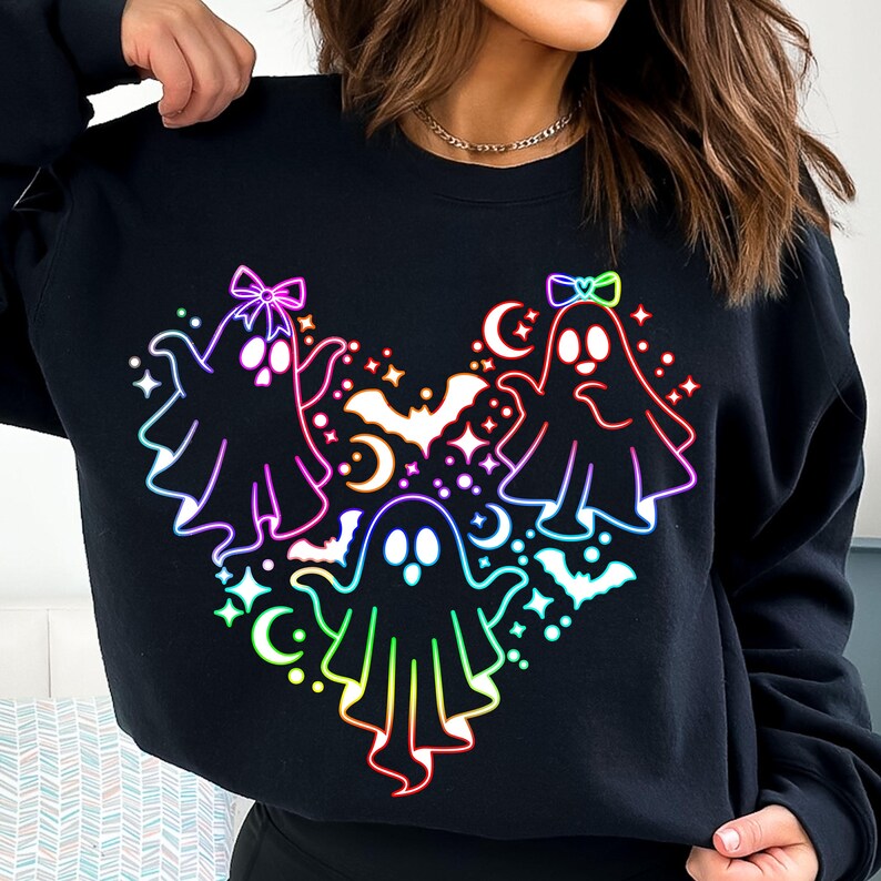 May include: Black sweatshirt with a rainbow-colored design of three ghosts with bows on their heads. The ghosts are arranged in a heart shape with stars and bats around them.
