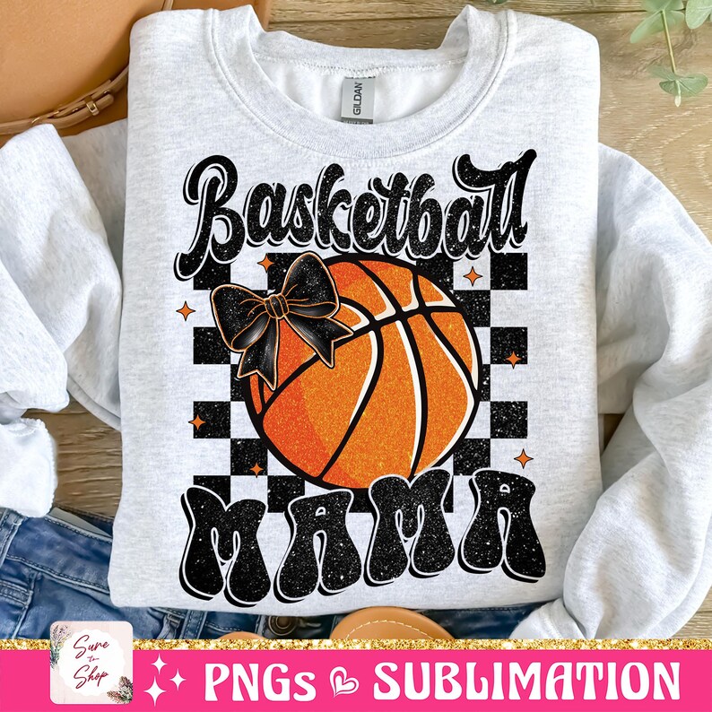 May include: A gray sweatshirt with a black and white checkered background. A basketball with a black bow is in the center of the checkered background. The text "Basketball Mama" is in black with glitter accents.