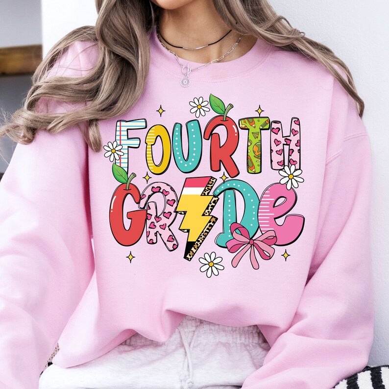 May include: Pink sweatshirt with a colorful graphic that says "FOURTH GRADE" with a rainbow, lightning bolt, hearts, and flowers.
