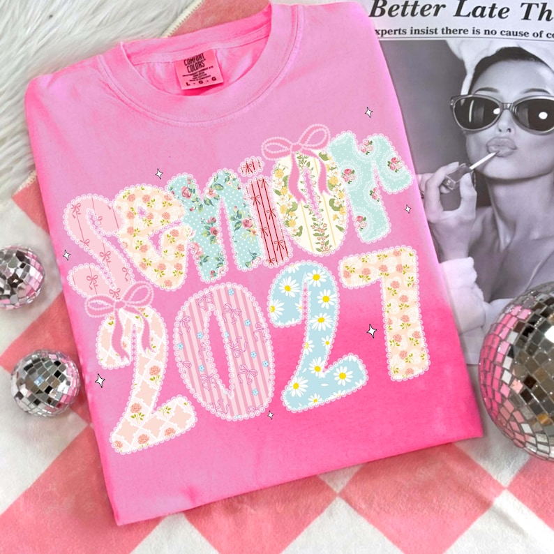 May include: A pink crew neck t-shirt with the word "SUMMIT 2021" in a patchwork design. The letters and numbers feature floral, striped, and polka dot patterns. The shirt has a Comfort Colors tag.