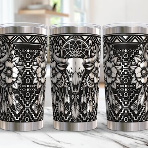 May include: Three stainless steel tumblers with a black and white design featuring a bull skull, dreamcatcher, feathers, and floral elements. The design is reminiscent of Native American art.