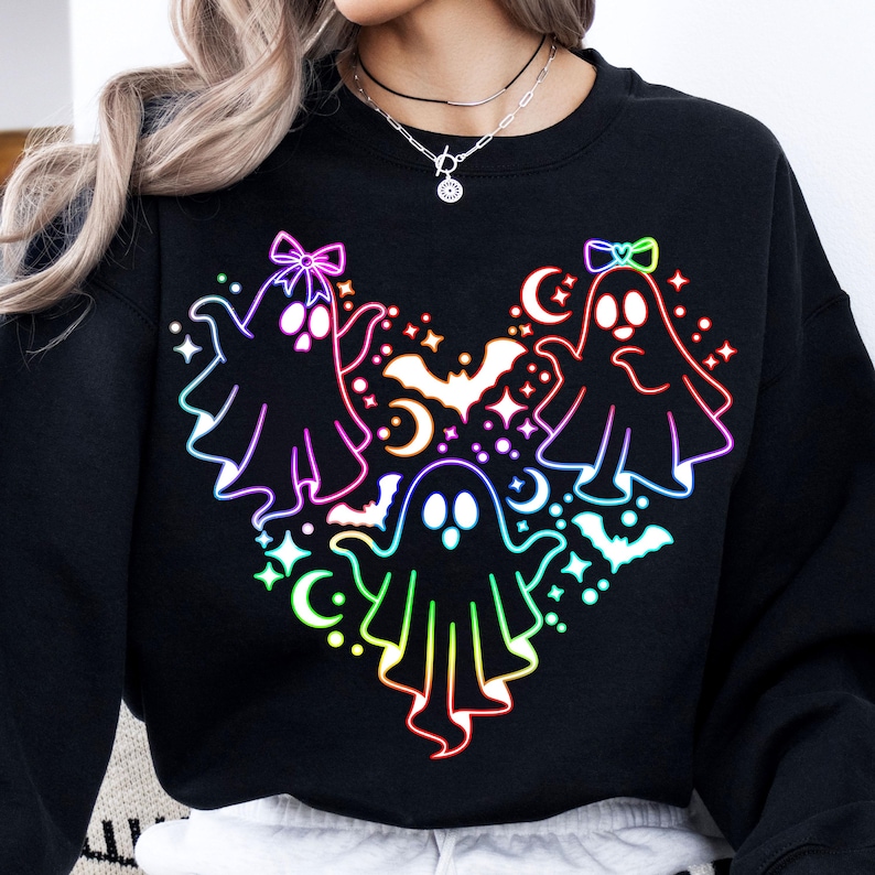 May include: Black sweatshirt with a rainbow-colored design of three ghosts with bows on their heads. The ghosts are arranged in a heart shape with bats and stars around them.