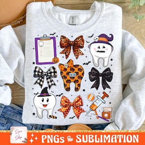 May include: A white sweatshirt with a Halloween-themed dental design. The design features a tooth with a witch's hat, a bow with orange and black polka dots, a tooth with a pumpkin design, a clipboard with a tooth icon, and a dental floss container.