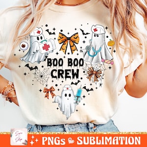 May include: A white t-shirt with a heart-shaped design featuring cute ghost nurses with medical supplies, a bow, and the text "BOO BOO CREW".