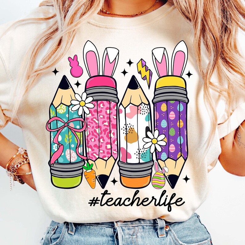 May include: White t-shirt featuring a graphic of four colourful pencils with bunny ears and the text "#teacherlife".