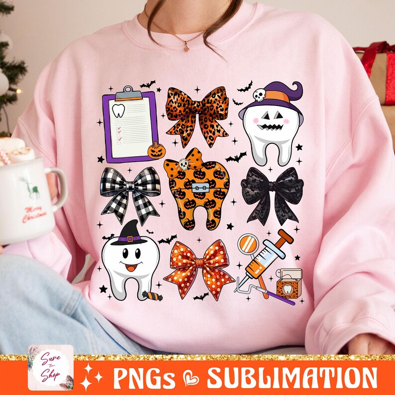 May include: A pink sweatshirt with a Halloween-themed dental design. The design features a variety of images, including teeth, bows, a clipboard, a syringe, and a mirror. The text "Sure to Shop" is visible in the lower left corner of the image.