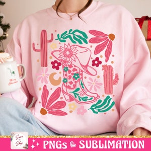 May include: Pink sweatshirt with a colorful graphic of a cowboy boot, hat, flowers, and cacti. The boot has a floral pattern. The design includes a sunflower, crescent moon, and various leaves. The text "PNGs & SUBLIMATION" is at the bottom.