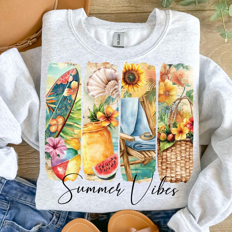 May include: A gray sweatshirt with a watercolor design of a beach scene. The design includes a surfboard, a beach chair, a basket of fruit, and a watermelon. The text "Summer Vibes" is printed below the design.