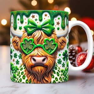 May include: A white ceramic mug with a green, white and gold design. The design features a cartoon Highland cow wearing green shamrock-shaped sunglasses and a green bow. The mug has a white handle.