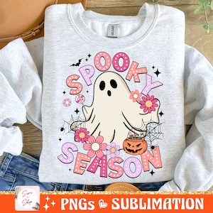 May include: A gray sweatshirt with a pink and white design featuring a ghost holding a lollipop, a pumpkin with candy, and the text "Spooky Season".