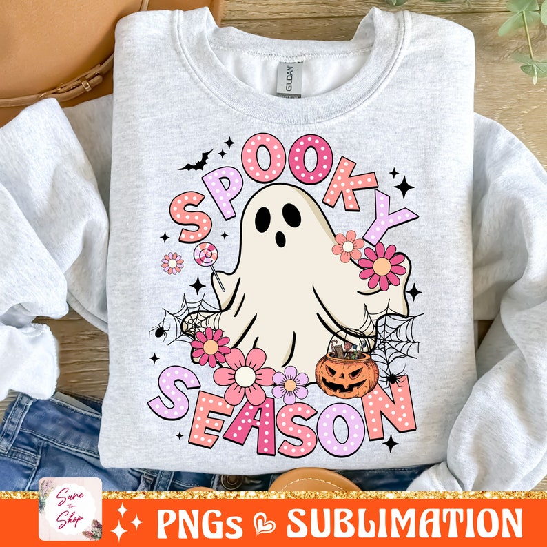 May include: A gray sweatshirt with a pink and white design featuring a ghost holding a lollipop, a pumpkin with candy, and the text "Spooky Season".