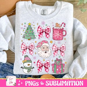 May include: A gray sweatshirt with a Christmas design featuring a green Christmas tree, Santa Claus, a snowman, a mug of hot chocolate, a gift box, and pink and white gingham bows.