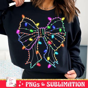 May include: Black sweatshirt with a white outline of a bow decorated with colorful Christmas lights.