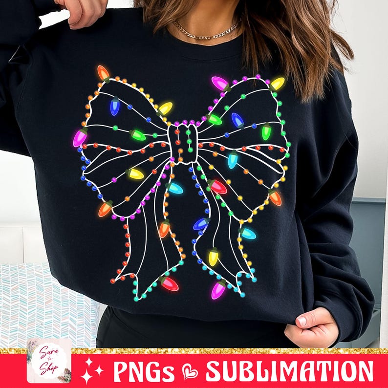 May include: Black sweatshirt with a white outline of a bow decorated with colorful Christmas lights.