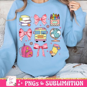 May include: A light blue sweatshirt with a design of school-themed illustrations. The design includes a school bus, a globe, a backpack, a pencil, crayons, books, and pink bows.