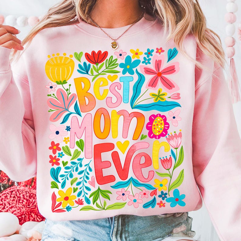 May include: Pink sweatshirt with a floral design and the text "Best Mom Ever" in colorful letters.