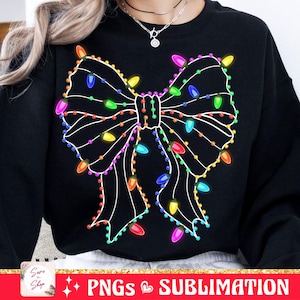 May include: Black sweatshirt with a white outline of a bow made of Christmas lights. The lights are multi-colored and include red, green, blue, yellow, orange, and purple.