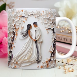 Pode incluir: Caneca de cer&acirc;mica branca com um design de papel cortado de um casal com um vestido de noiva e um terno de p&eacute; em frente a um arco floral. O design &eacute; em tons de branco, marrom e dourado.