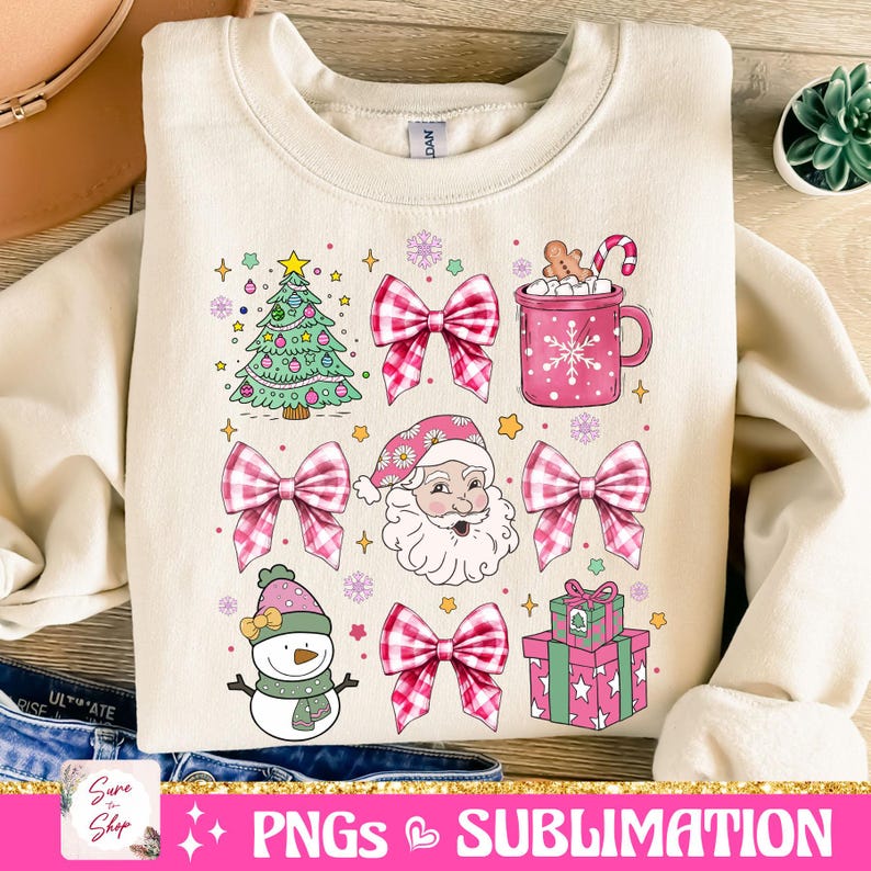 May include: A cream-colored sweatshirt with a Christmas-themed design. The design features a green Christmas tree, a snowman, Santa Claus, pink and white gingham bows, a pink mug with marshmallows and a candy cane, and a pink gift box with green wrapping paper.