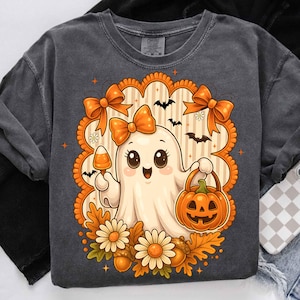 Pode incluir: Camisola cinza escuro com um design de fantasma de desenho animado segurando uma ab&oacute;bora e doces de milho. O fantasma &eacute; cercado por la&ccedil;os laranja, morcegos, flores e folhas de outono. O design tem um estilo vintage de desenho animado, perfeito para o Halloween.
