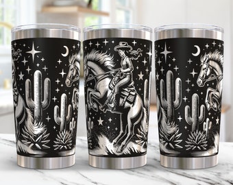 May include: A black and white stainless steel tumbler with a design of a cowgirl riding a horse in front of cacti and stars.