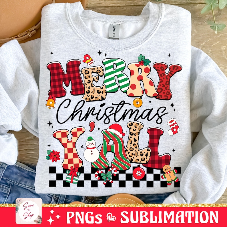 Pu&ograve; includere: Una felpa grigia con un design natalizio festoso. Il testo "Merry Christmas Y'all" &egrave; scritto in lettere colorate e con motivi. Il design include un pupazzo di neve, un cappello di Babbo Natale e un omino di pan di zenzero.