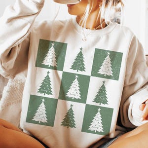 May include: A white sweatshirt with a green and white checkered pattern featuring a repeating design of stylized Christmas trees.